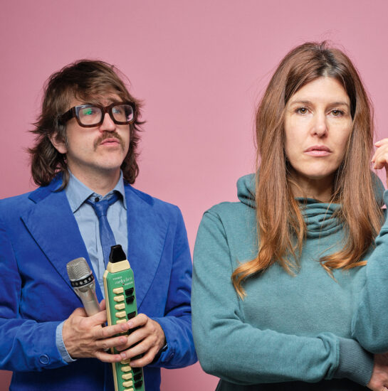 Une femme ne sourit pas et un homme la regarde avec des instruments de musique dans les mains