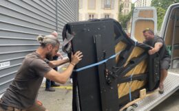 Deux personnes glissent le piano sur la rampe du camion